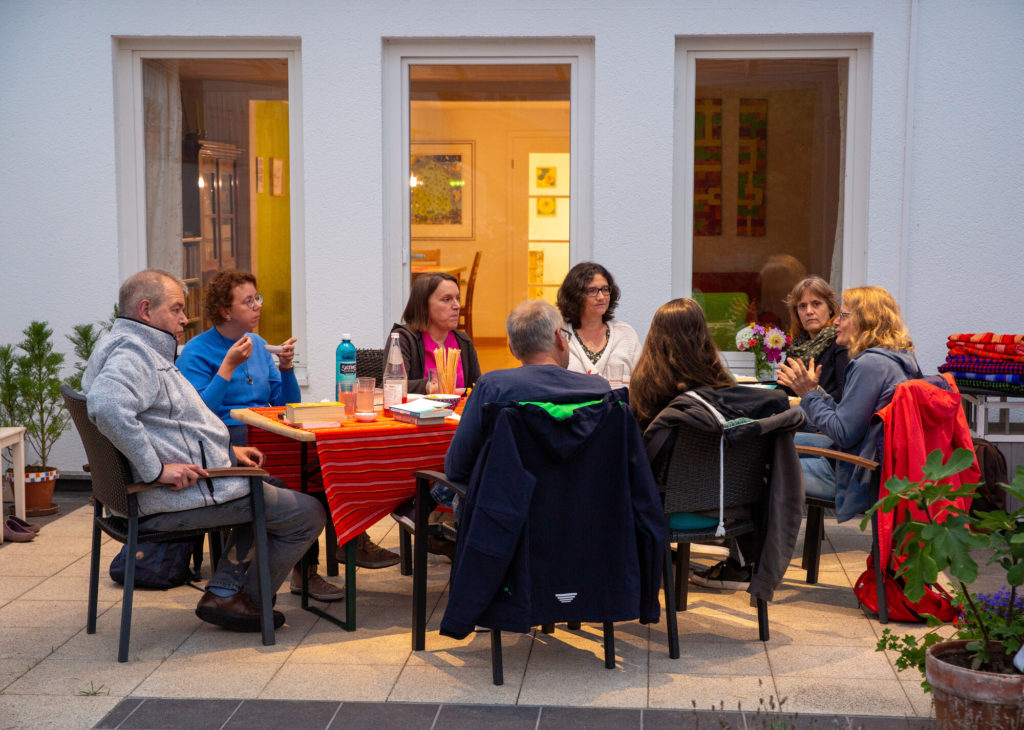mehrere Personen sitzen an einem Tisch und unterhalten sich