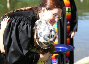 Kind mit buntem Hut umarmt evangelische Pfarrerin